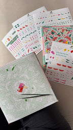 Collection of colorful stationery items including notebooks and stickers on a neutral background