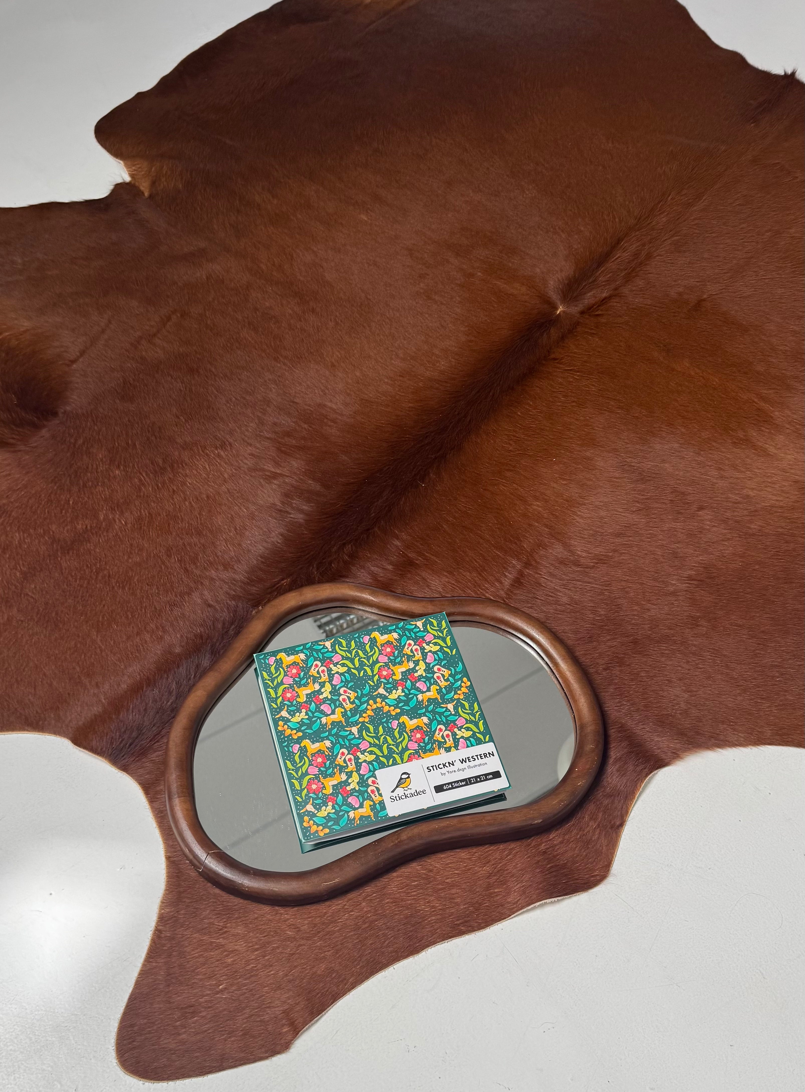 Mirror with floral design on a brown leather surface